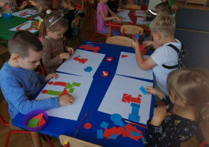 Dzieci siedzą przy stoliku i pracują z figurami geometrycznymi